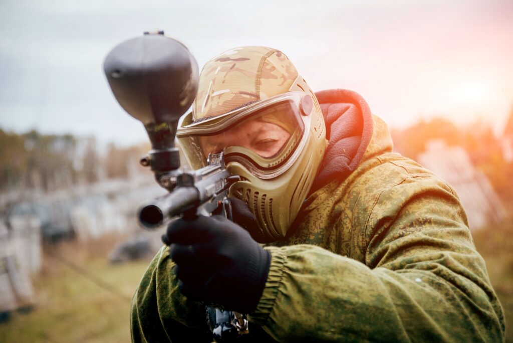 Ein Mann in Schutzkleidung mit einer Paintball Waffe in der Hand