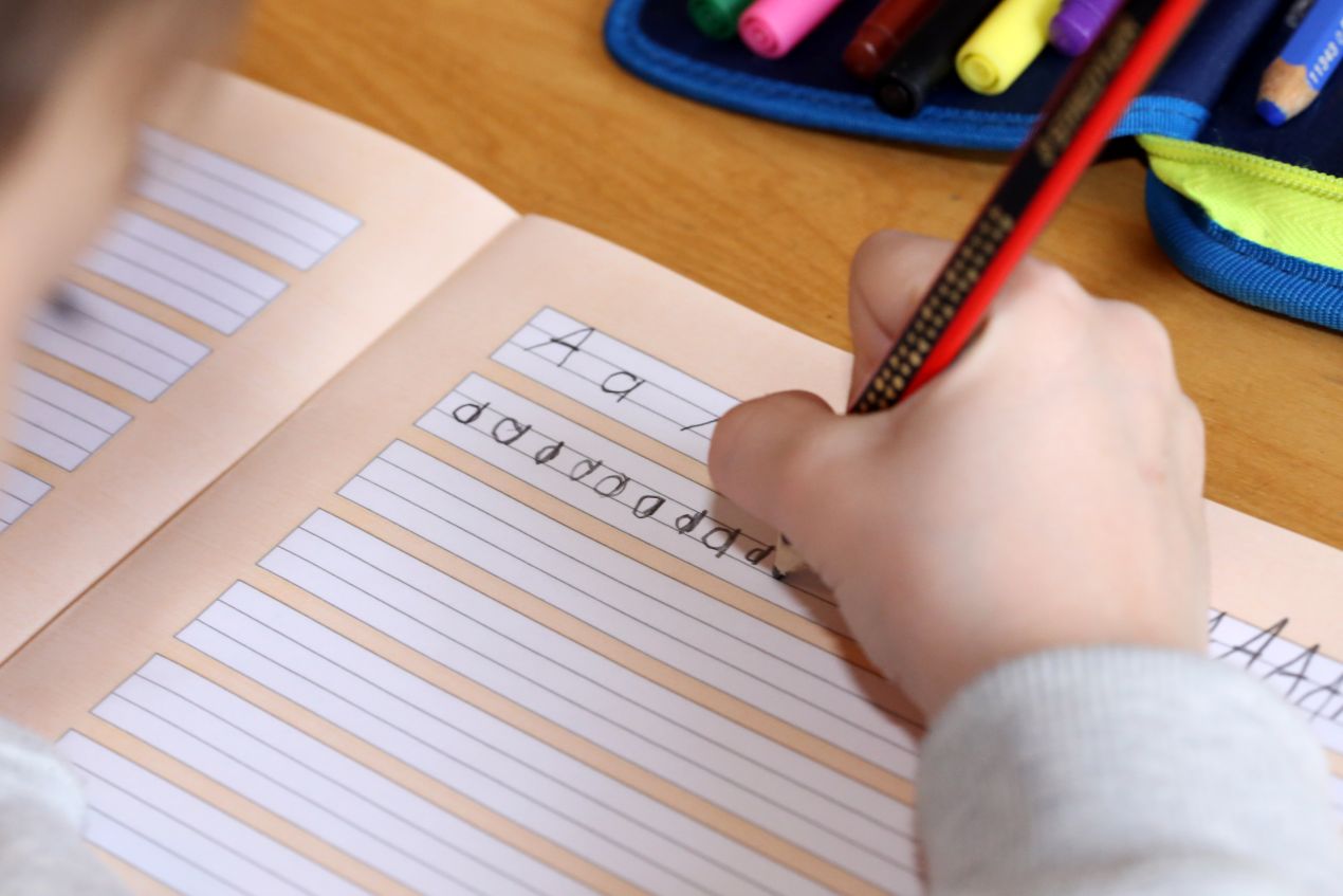 Kind schreibt Buchstaben in ein Schulheft – frühe Schreibförderung an einer private grundschule in berlin