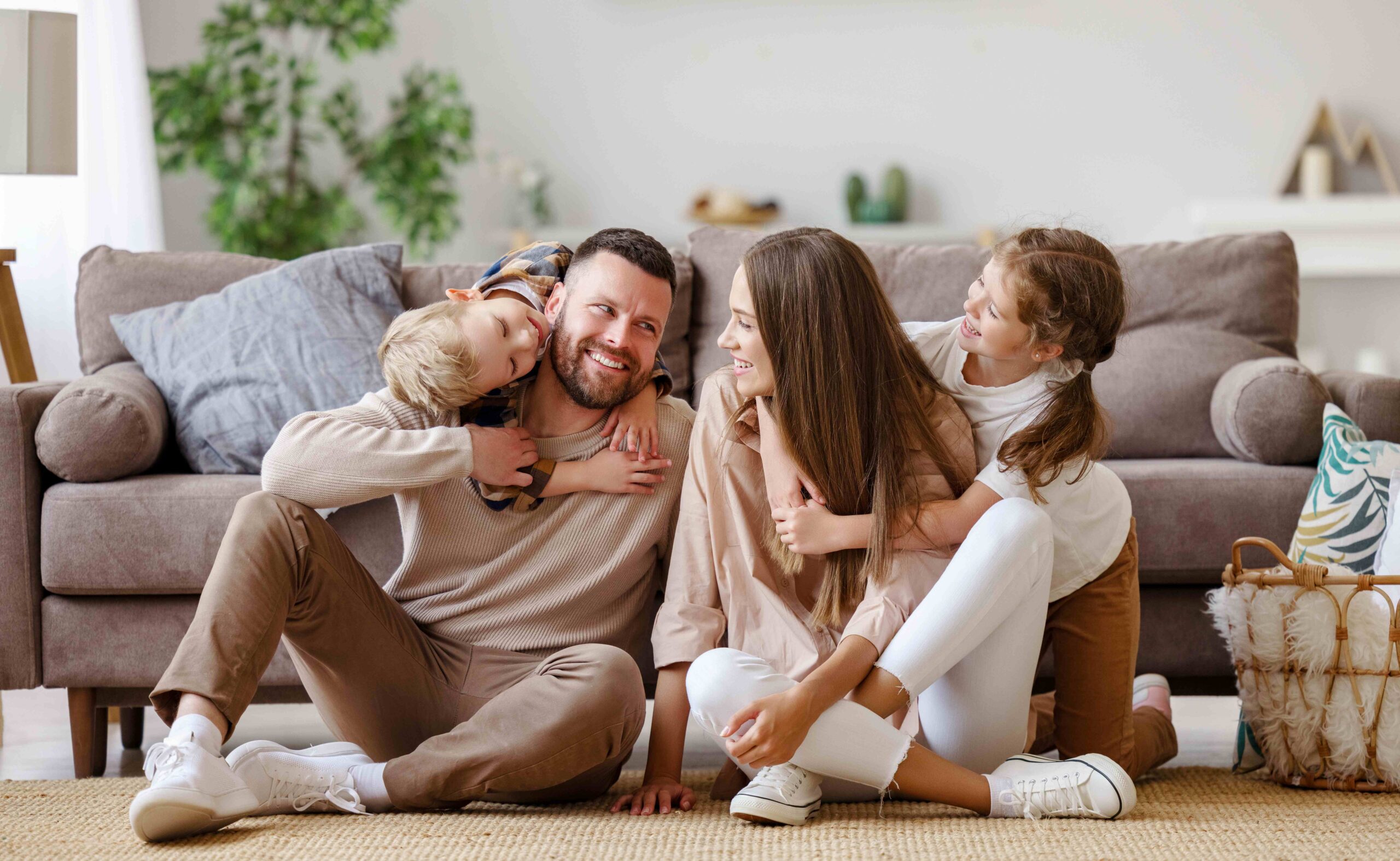 Glückliche Familie: Mutter, Vater und Kinder zu Hause auf dem Boden neben dem Sofa.