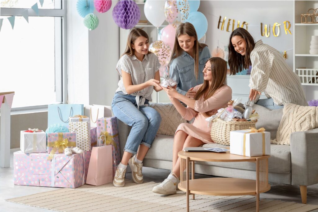 Junge schwangere Frau erhält von ihren Freunden auf der Babyparty einen Geschenkkorb